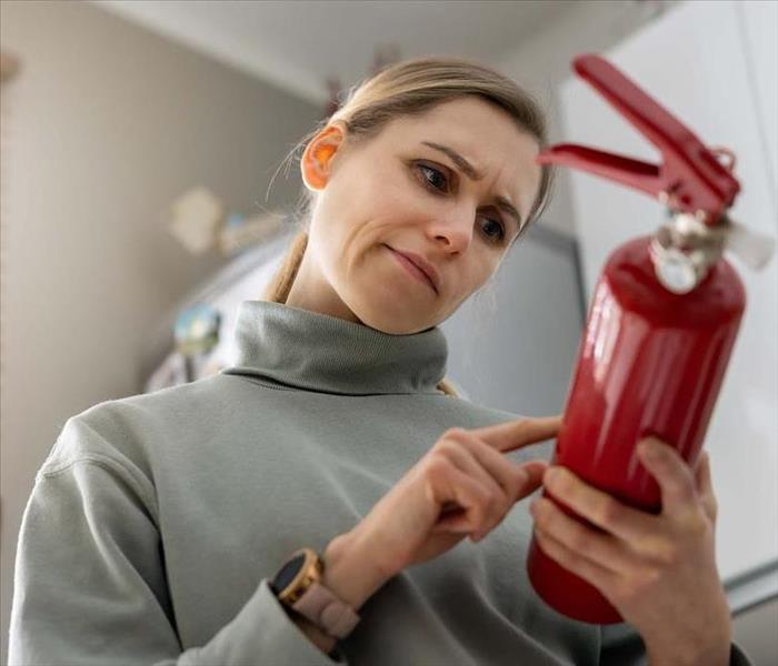 Woman checking Fire Extinguisher in Home
