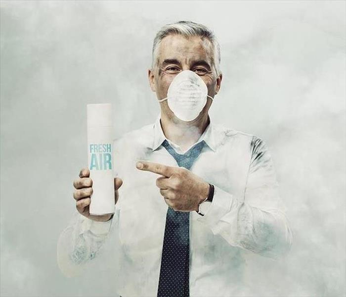 Man Holding Air Freshener while surrounded by Smoke